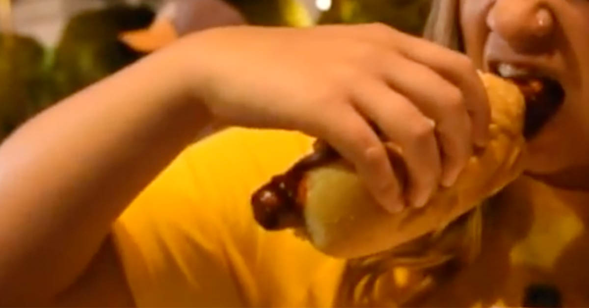 une fille mange un hotdog